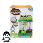 یک اسباب‌بازی پلاستیکی سبز رنگ به شکل قورباغه ماجراجو با دهان باز که روی یک سطح روشن قرار گرفته است. در کنار قورباغه، چندین سکه پلاستیکی رنگارنگ دیده می‌شود که آماده پرتاب شدن هستند. تصویر، حس یک بازی شاد، پرانرژی و آموزشی را برای کودکان خردسال القا می‌کند.